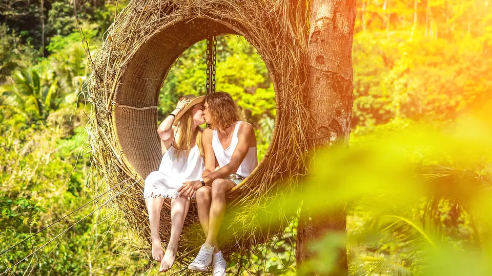 Sexdate Aarau: Paar küsst sich in einer Hängeschaukel im Grünen