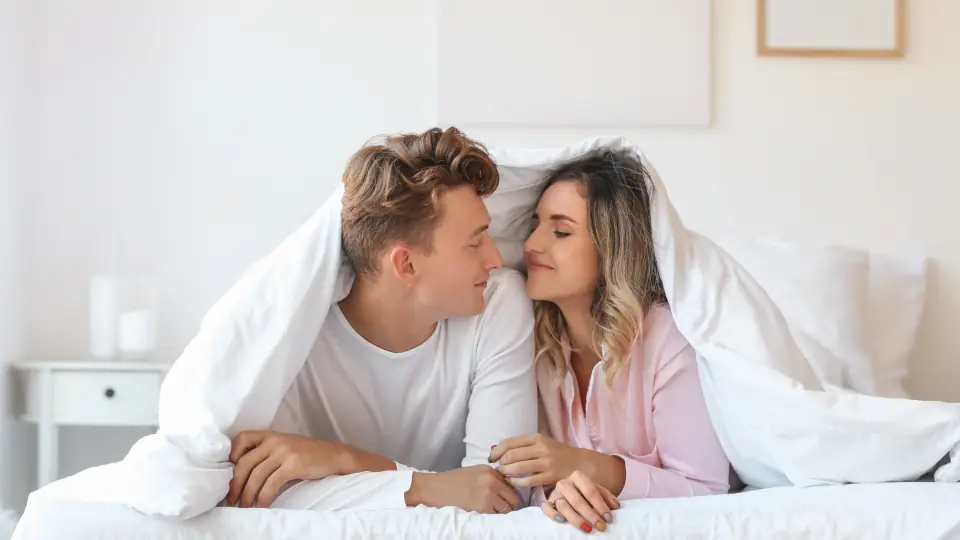 Sexdate Schwyz: Paar liegt lachend unter der Bettdecke